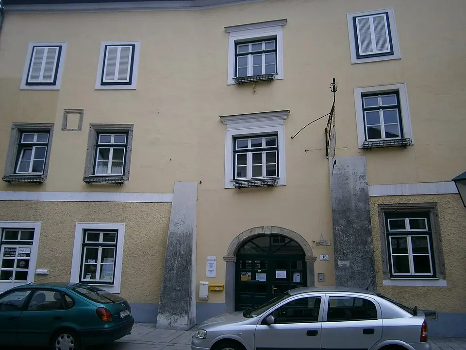 Gasthaus Tröls, ehem. Zur Goldenen Sense mit Wirtshausschild und Stadtmauerteil