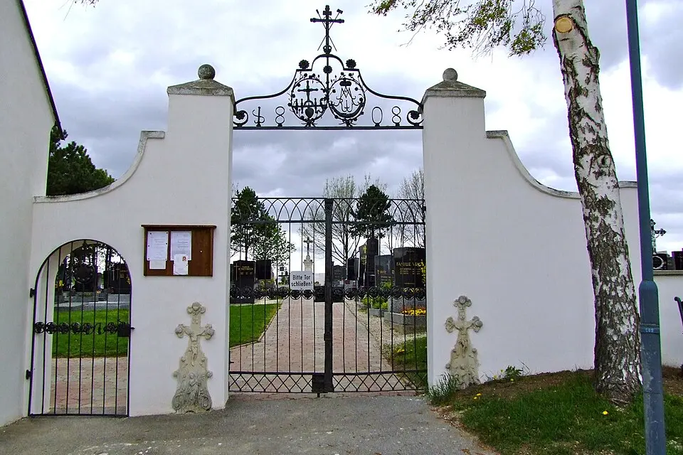 Friedhofstor mit Gitter und Grabstein